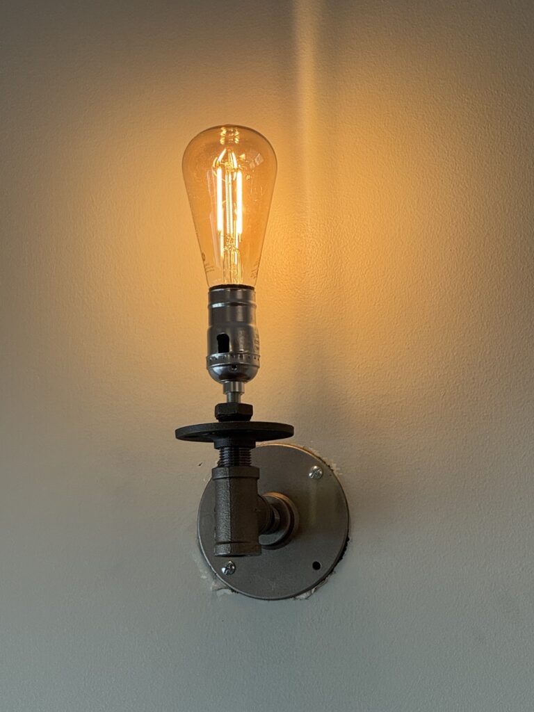 Custom industrial Edison bulb pipe fixture installed on finished wall