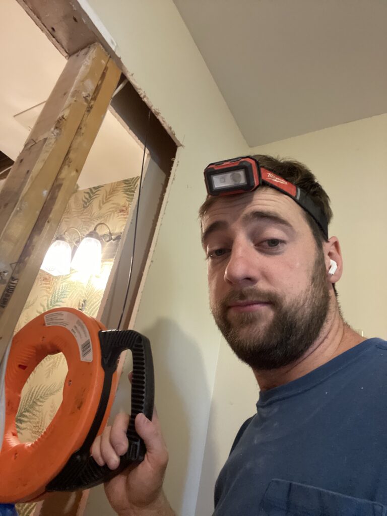 Joe Holder running new wire through open wall framing