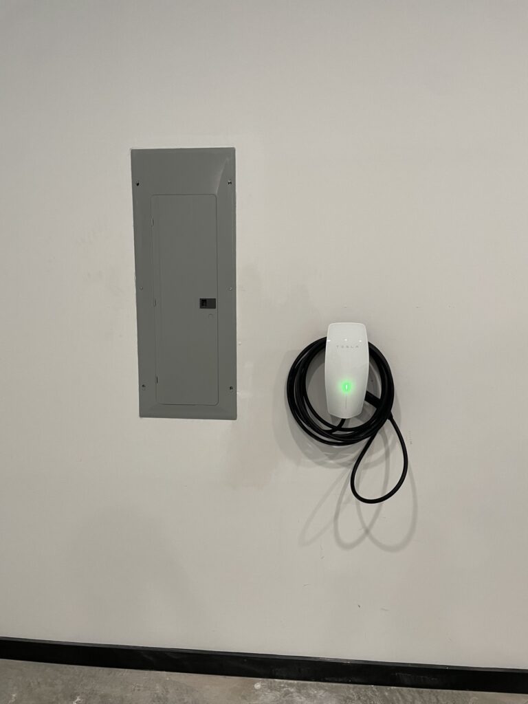 Tesla Wall Connector Level 2 EV charger installed next to electrical panel
