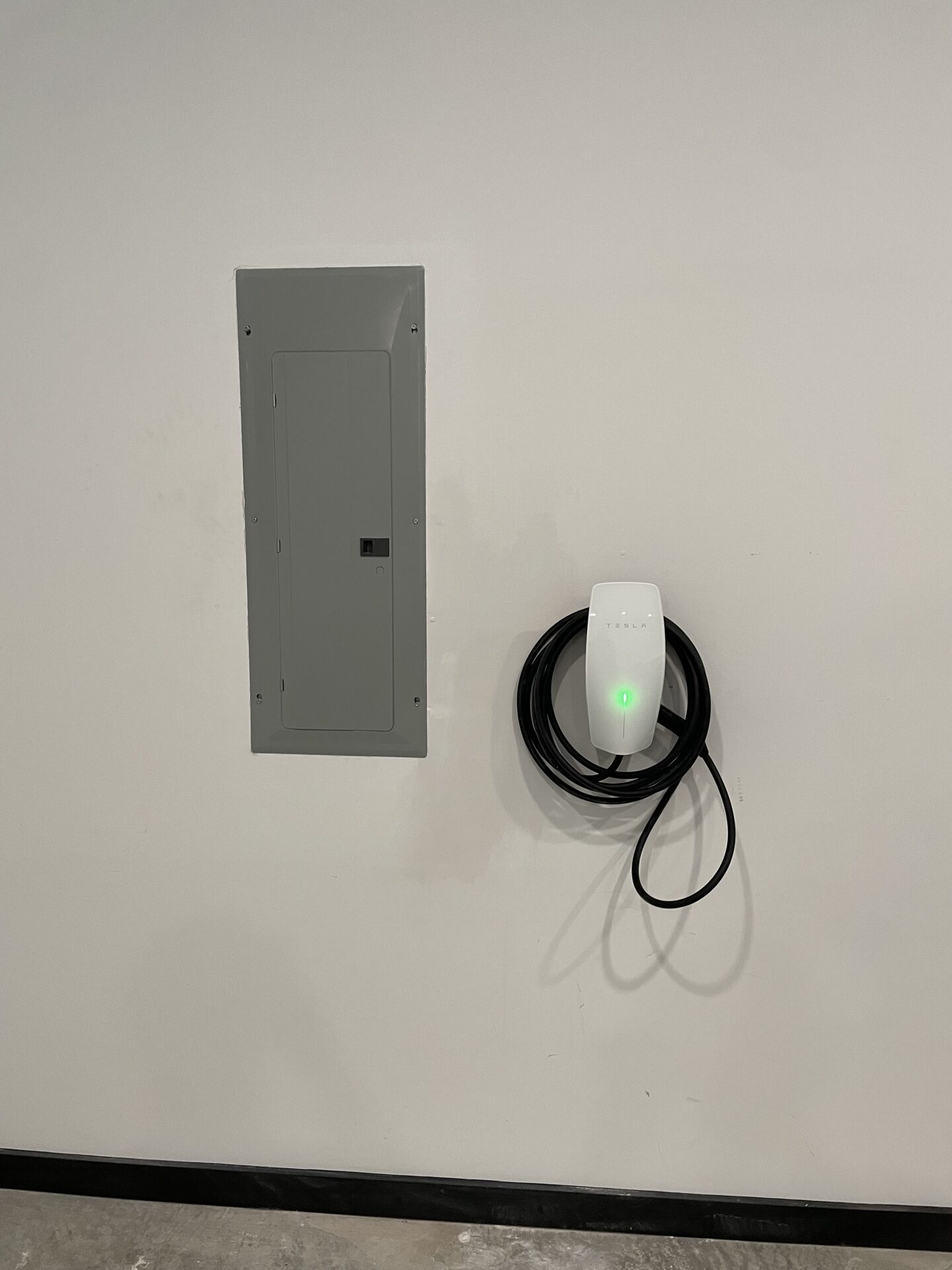 Tesla Wall Connector Level 2 EV charger installed next to electrical panel
